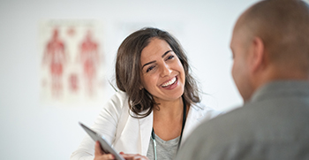 A close-up of a smiling female doctor talking to her male patient