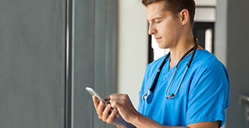 A doctor happily entering patient data into the EHR on their mobile device